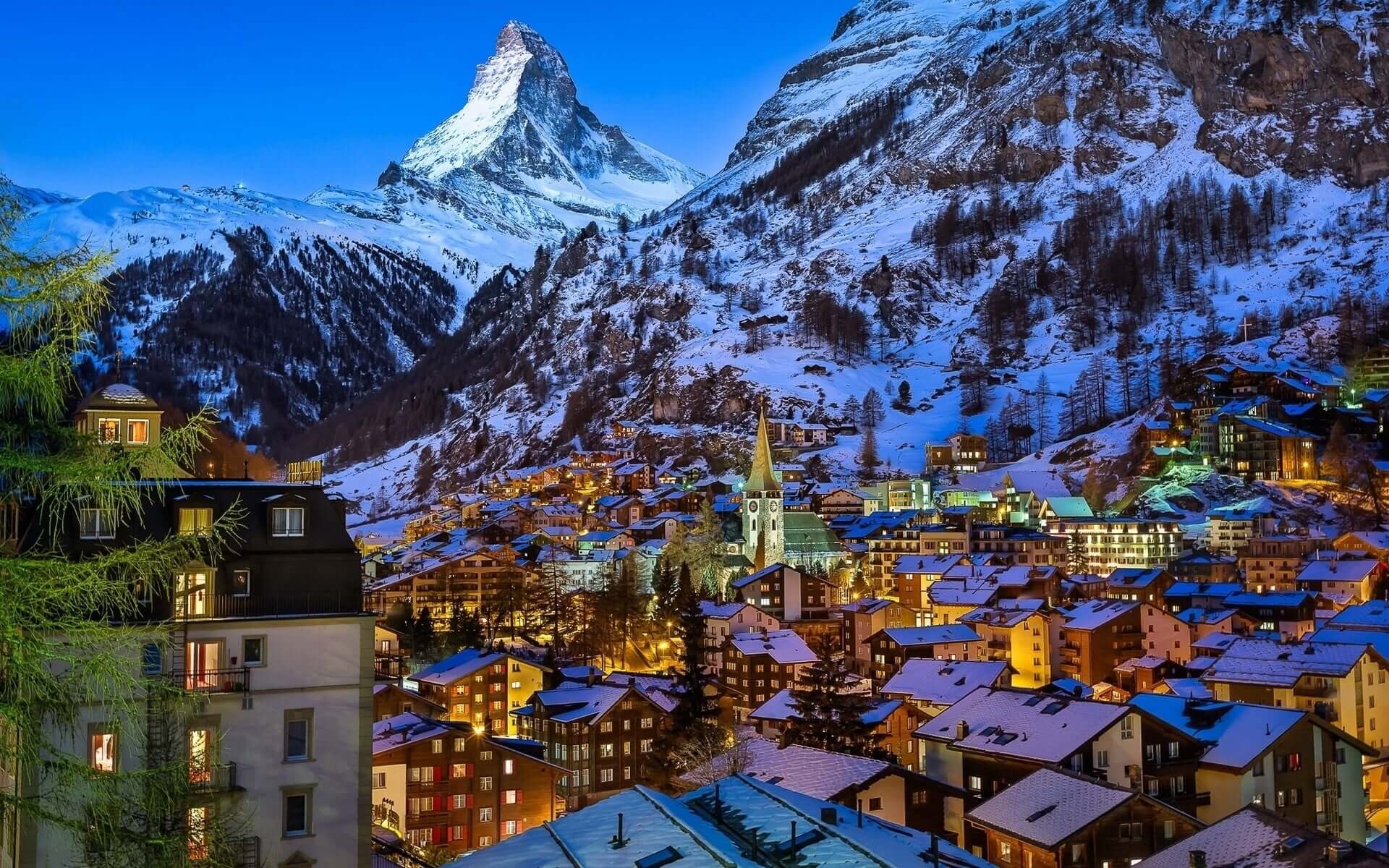 A beautiful city in the snowy mountains with lights glowing in the houses.